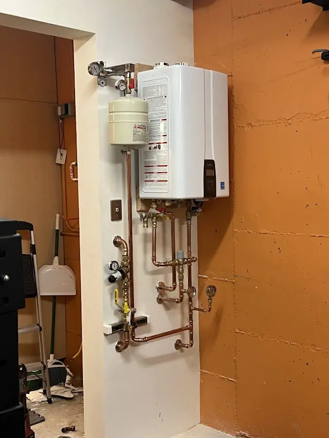 Plumbing technician inspecting water heater connections in Camas